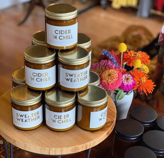 Candles 6 amber jars Gia Roma stacked on a wood stand with a bouquet on Tampa Home & Garden Store