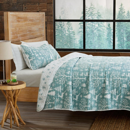 Lodge Woods Quilt by Great Bay Home in teal woodland pattern on a bed on Tampa Home & Garden Store