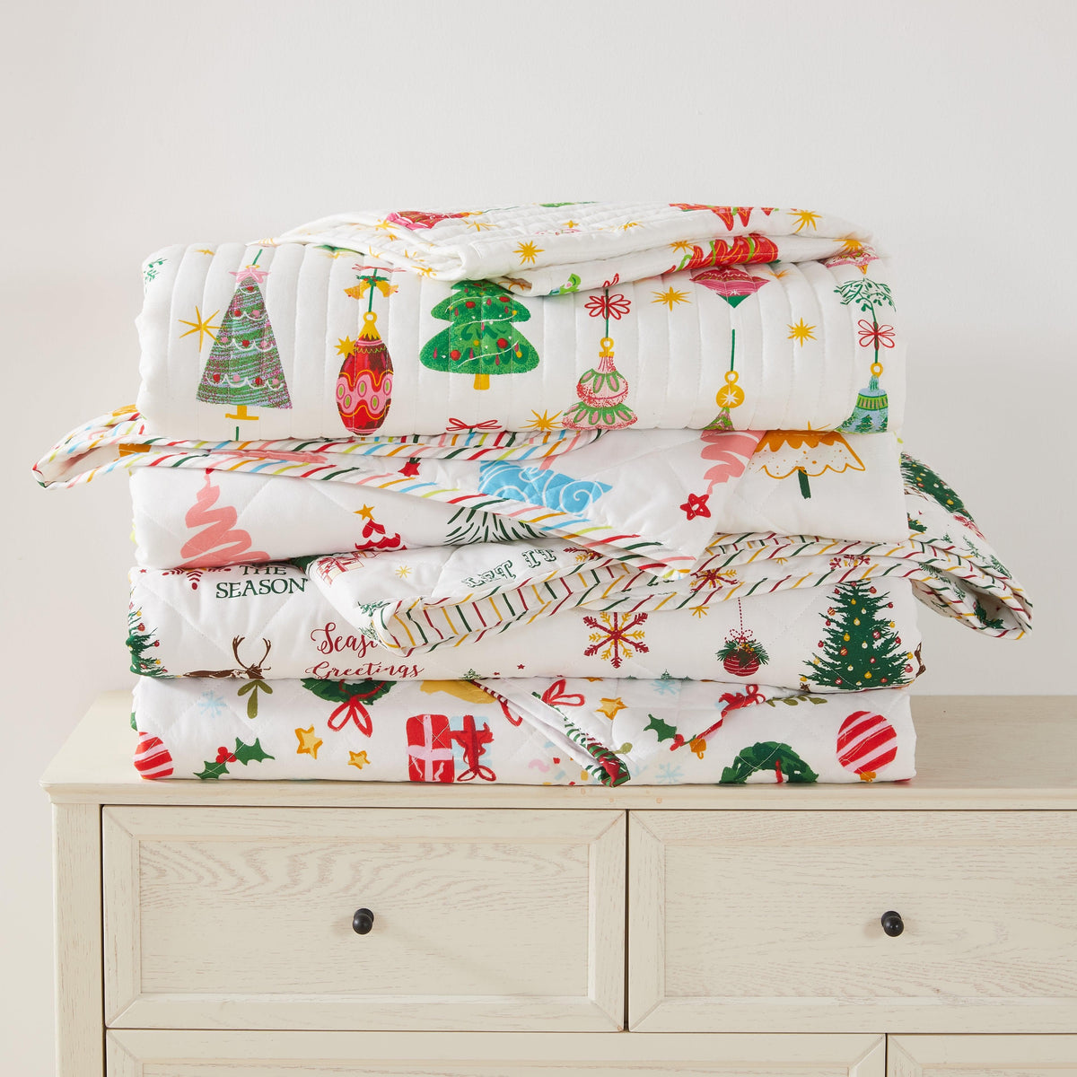 Colorful Holiday Quilt Set by Great Bay Home on a stack of festive quilts with Christmas trees on Tampa Home & Garden Store