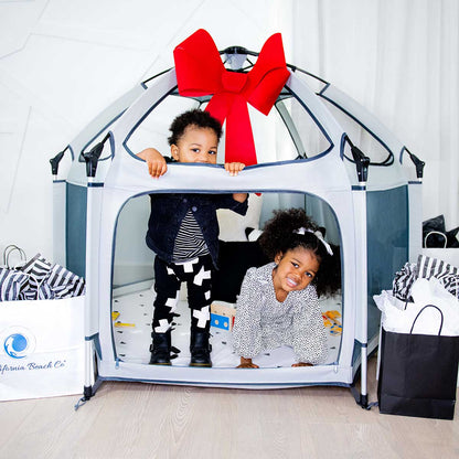 Pop 'N Go Playpen play yard in grey with a red bow and two kids inside California Beach Co LLC on Tampa Home & Garden Store