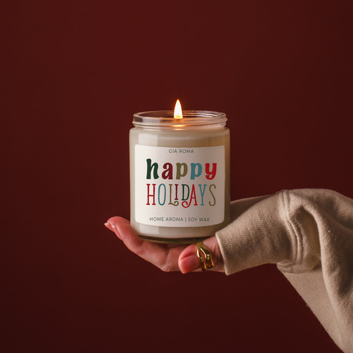 Happy Holidays candle by Gia Roma in a clear glass jar with white wax, held in beige sleeve on Tampa Home & Garden Store