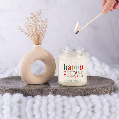 Candle Gia Roma Happy Holiday Candle in a clear jar beside a beige vase with pampas grass on Tampa Home & Garden Store