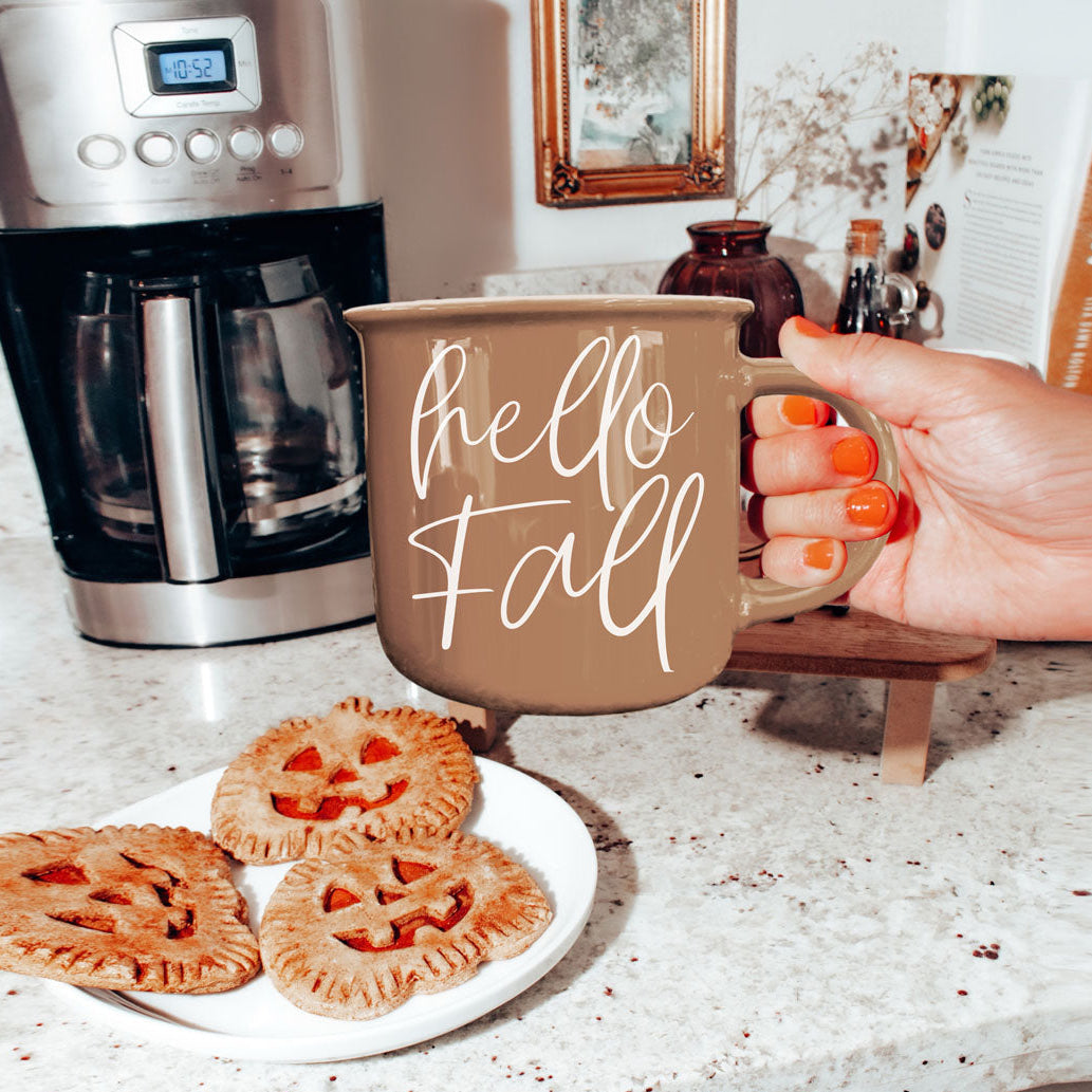 Hello Fall mug by Gia Roma, taupe ceramic coffee mug with white script; three pumpkin cookies on plate on Tampa Home & Garden Store