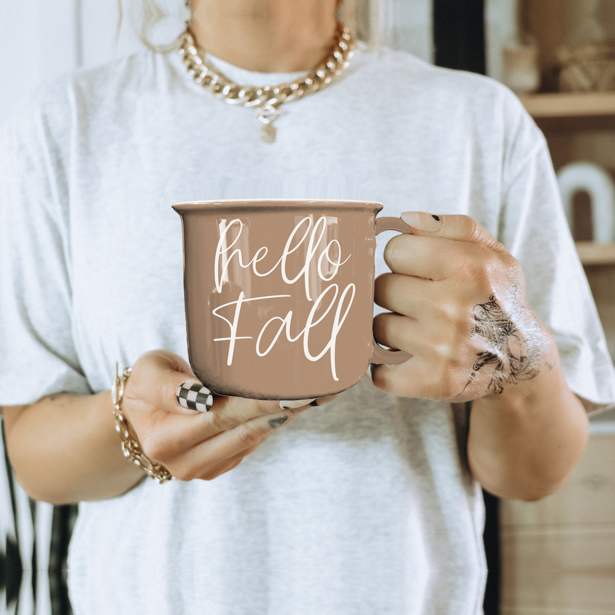 Hello Fall coffee mug in taupe ceramic with white script, held in hands with tattoos on Tampa Home & Garden Store