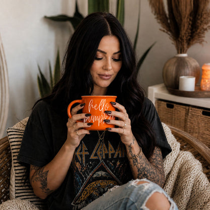 Hello Pumpkin coffee mug by Gia Roma, orange ceramic with white script, held by woman on Tampa Home & Garden Store