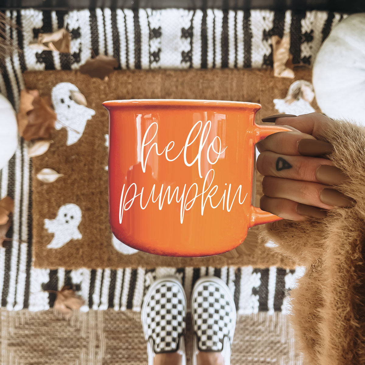 Hello Pumpkin mug in orange with white script held by hand on autumn rug on Tampa Home & Garden Store