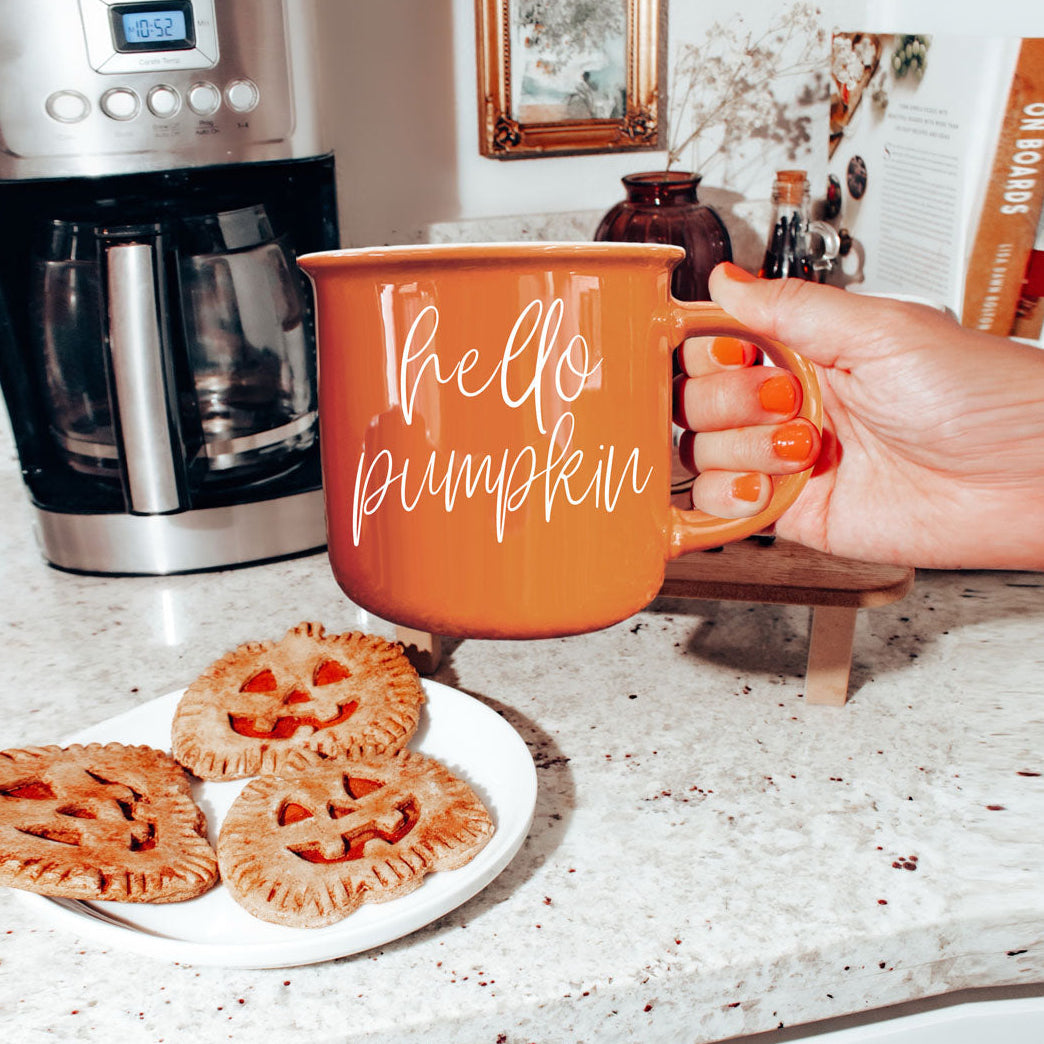 Hello Pumpkin mug Gia Roma orange ceramic with white script, hand near pumpkin cookies on Tampa Home & Garden Store