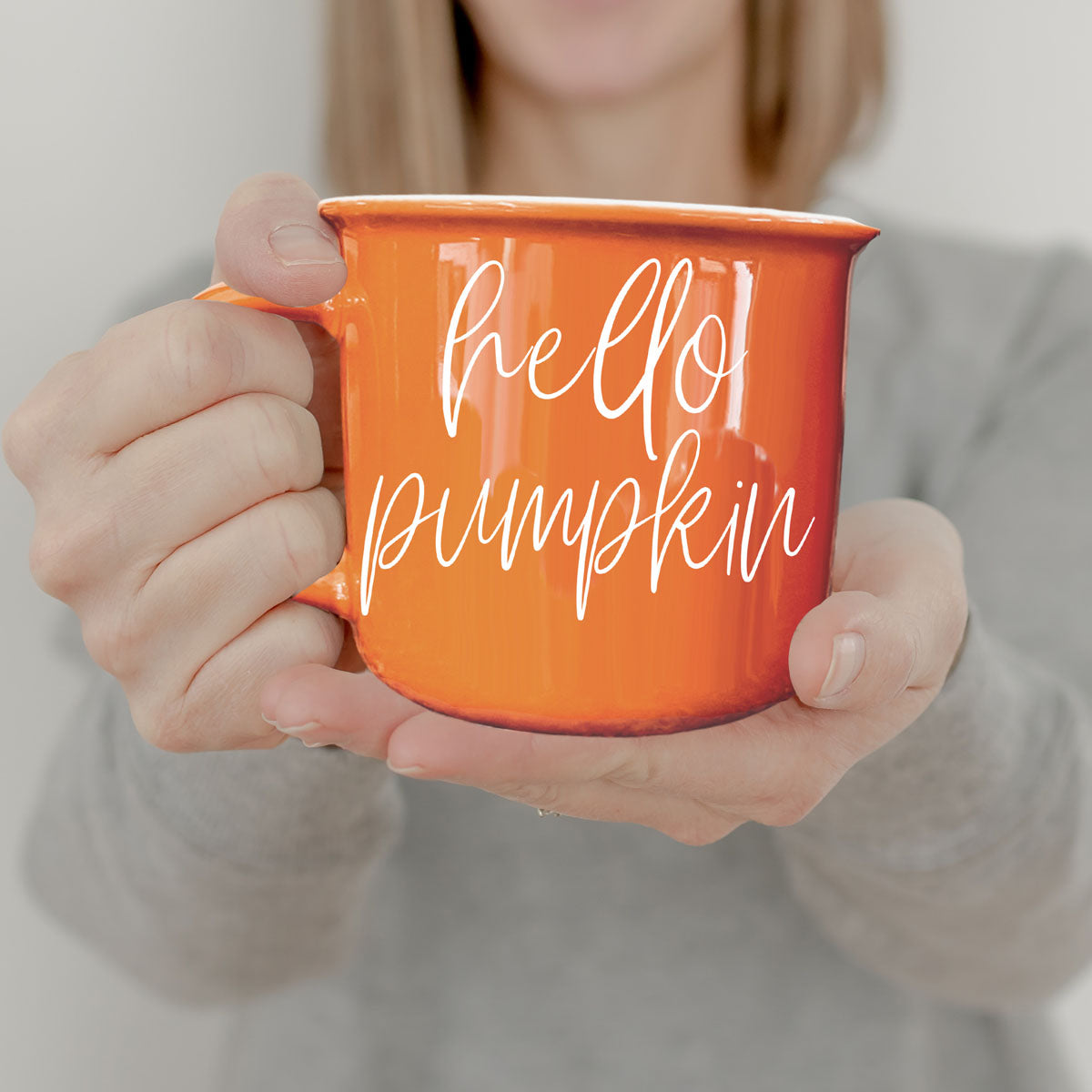 Hello Pumpkin coffee mug by Gia Roma in bright orange ceramic, held by hands on Tampa Home & Garden Store