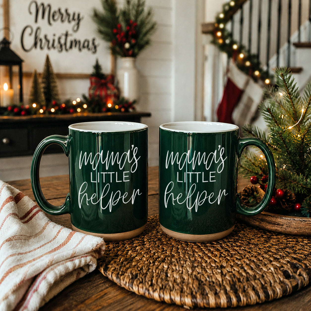 Two dark green Gia Roma Mama's Little Helper coffee mugs with white script on a holiday table on Tampa Home & Garden Store