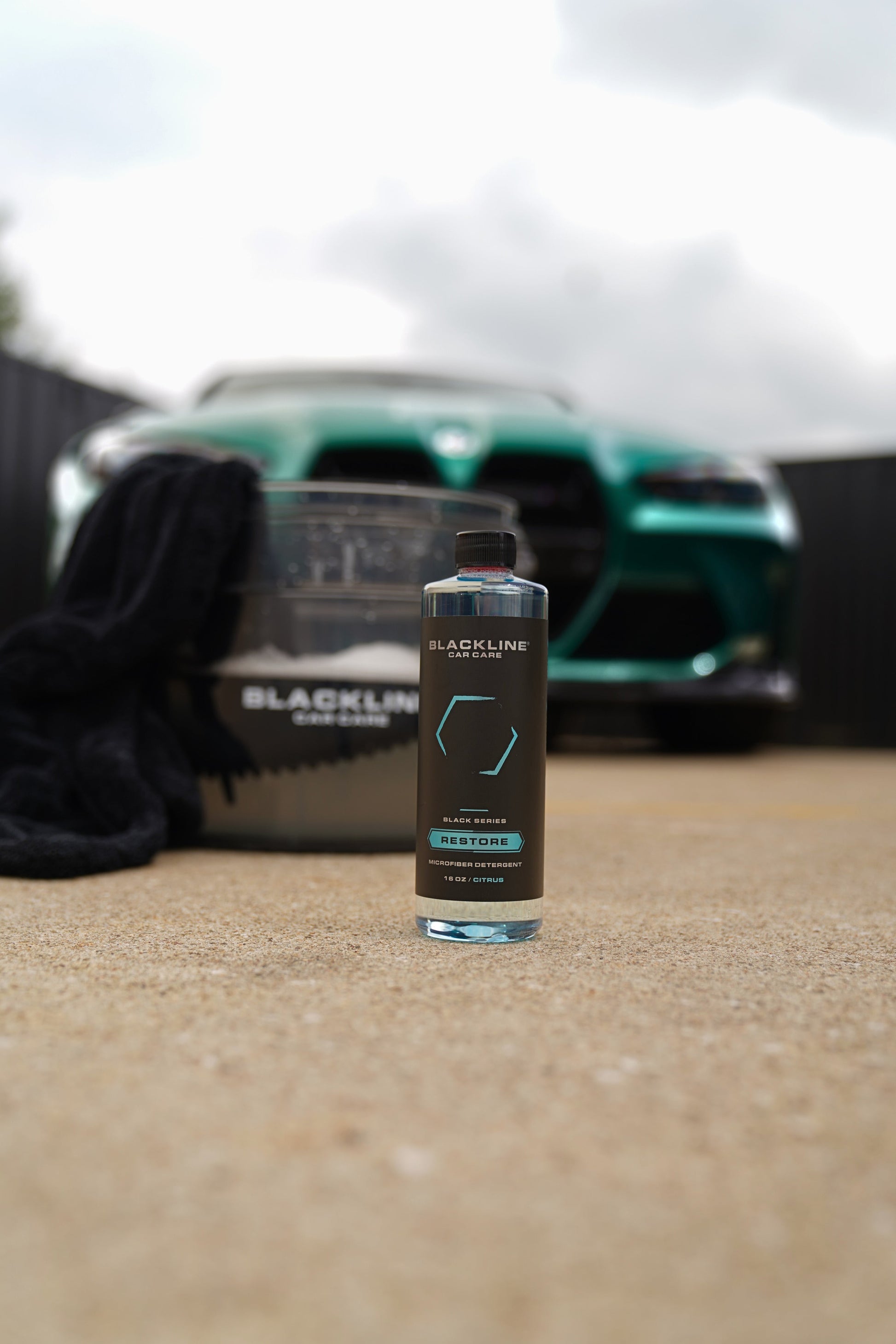 BLACKLINE black Restore Microfiber Detergent bottle front and center with blurred green car behind on Tampa Home & Garden Store
