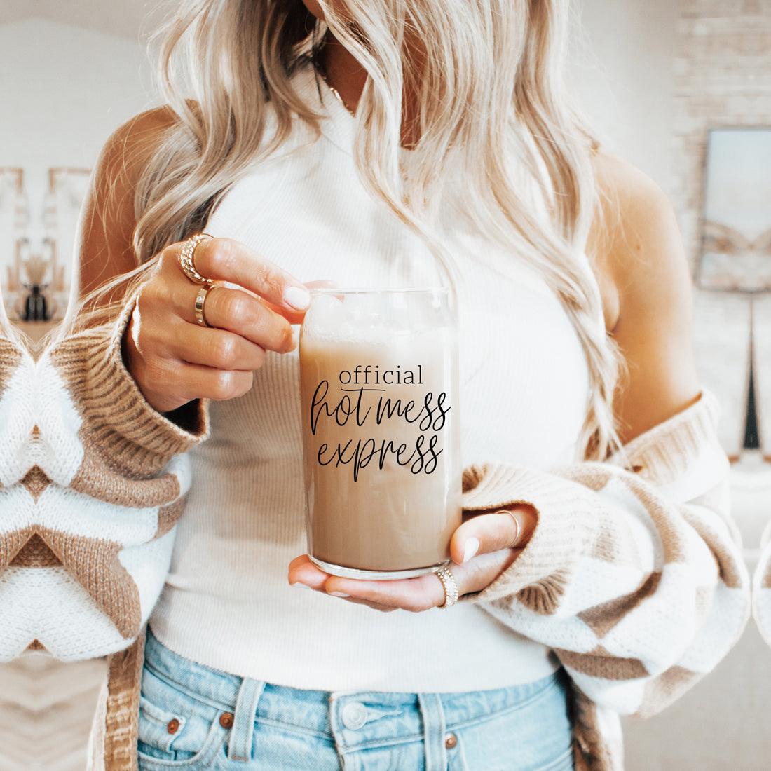 Hot Mess 17oz travel mug by Gia Roma, clear glass tumbler with beige drink held by a woman on Tampa Home & Garden Store