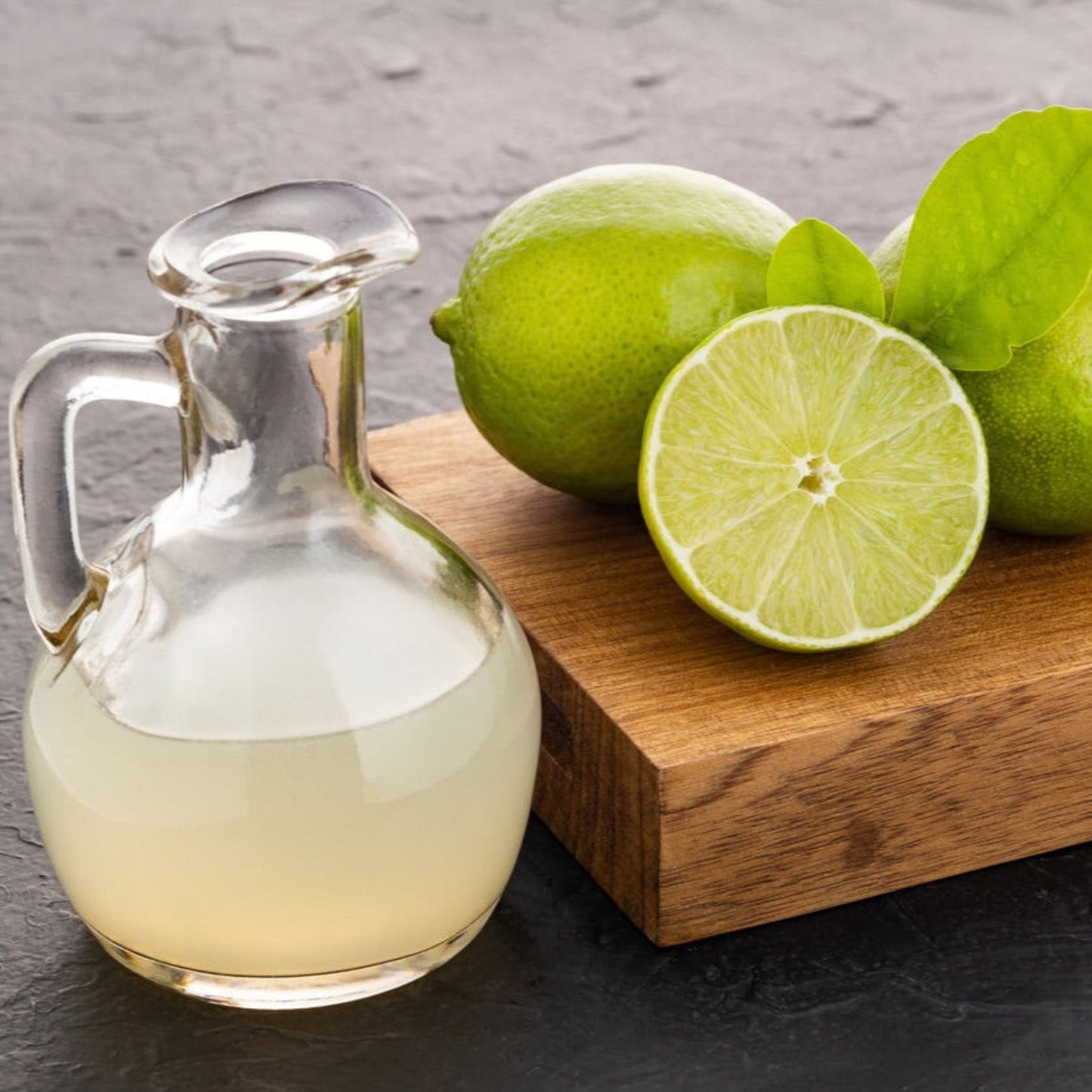 Persian Bearss lime fruits with lime halves and a clear glass pitcher on a wooden table on Tampa Home & Garden Store