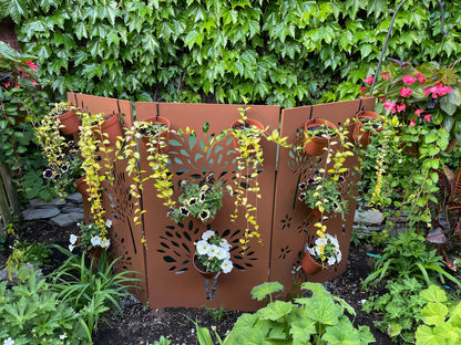 Outdoor privacy screen in rust-brown metal with leaf-cutout panels and hanging planters on Tampa Home & Garden Store