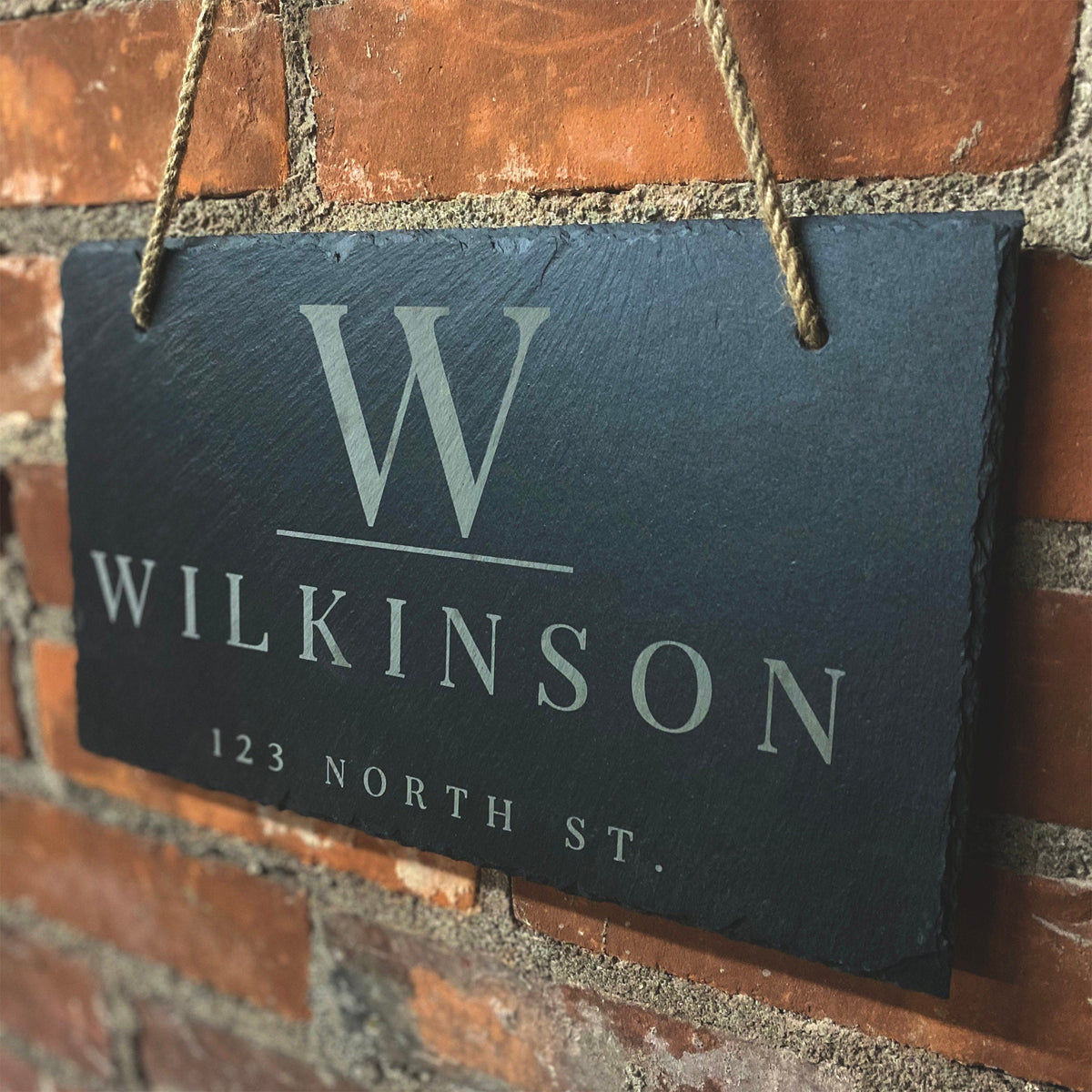 Personalized slate address sign with last name Wilkinson, white lettering, rope hanger on brick on Tampa Home & Garden Store