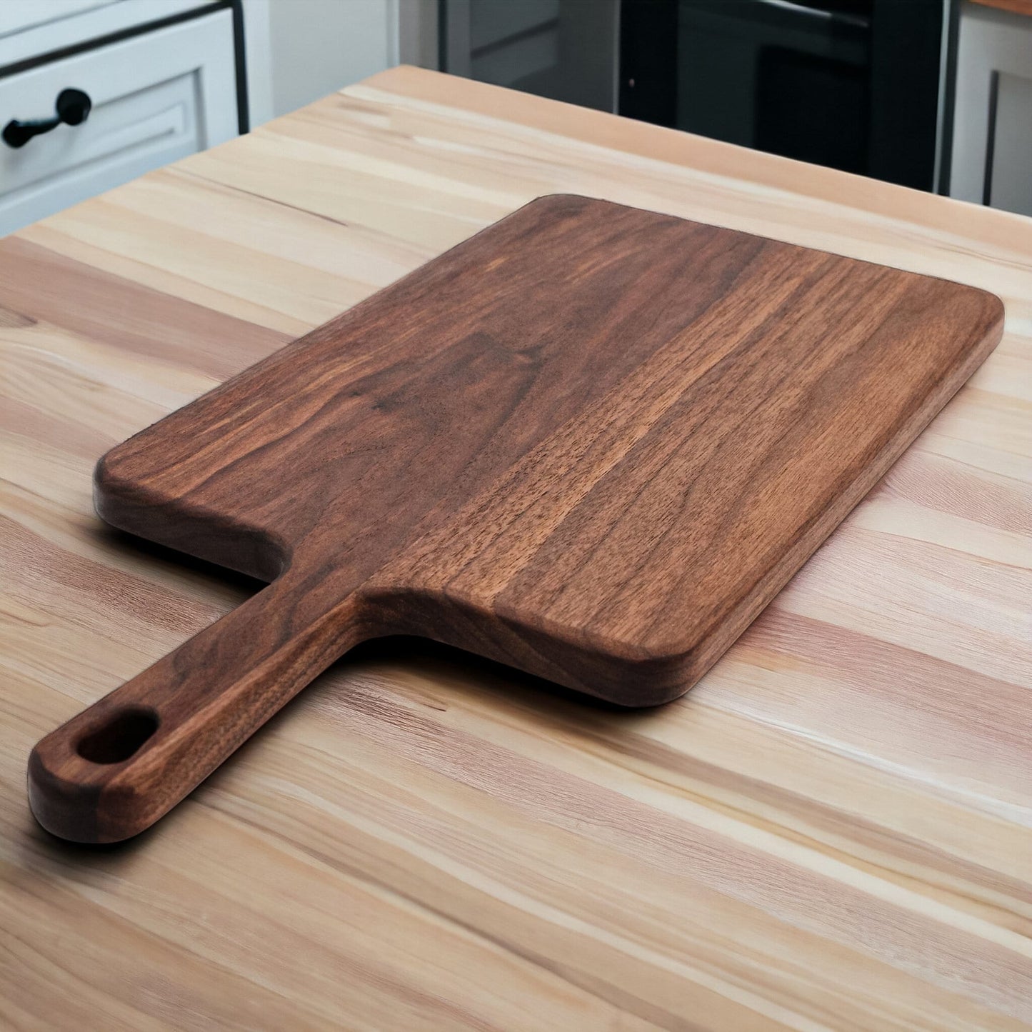 Walnut paddle cutting board with handle by Refine Kitchenware on light wood counter on Tampa Home & Garden Store