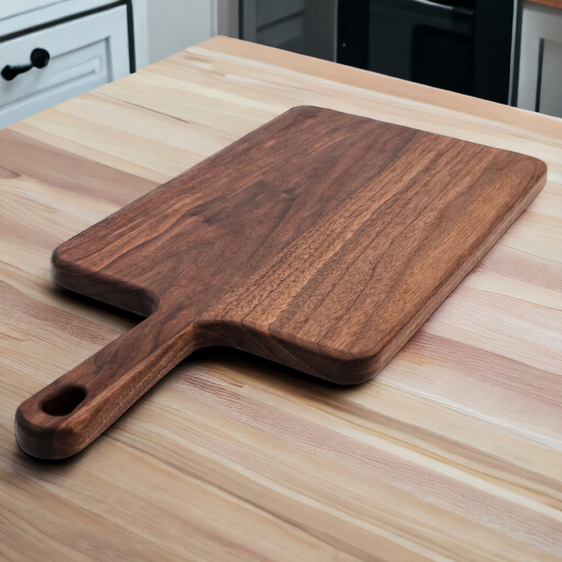 Walnut paddle cutting board with handle by Refine Kitchenware on light wood counter on Tampa Home & Garden Store