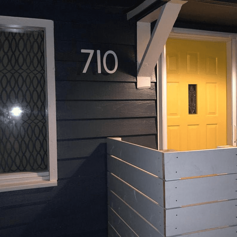 Rustica Ornamentals mission style house numbers set of 4 in white metal on siding beside yellow door on Tampa Home & Garden Store