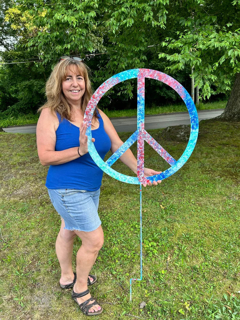 Outdoor peace sign ornament, tie-dye blue circle on a stake held by a woman in a blue top on Tampa Home & Garden Store