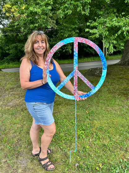 Outdoor peace sign ornament, tie-dye blue circle on a stake held by a woman in a blue top on Tampa Home & Garden Store