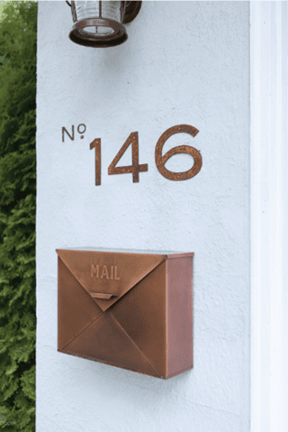 Metal house numbers Blair by Rustica Ornamentals 146 brown copper finish mounted on white wall on Tampa Home & Garden Store