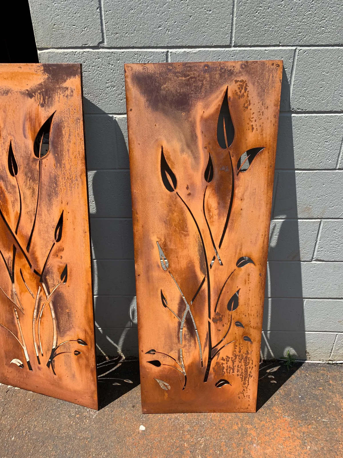Outdoor metal privacy screen panels pair with leaf-cutouts in rusted steel by Rustica Ornamentals on Tampa Home & Garden Store