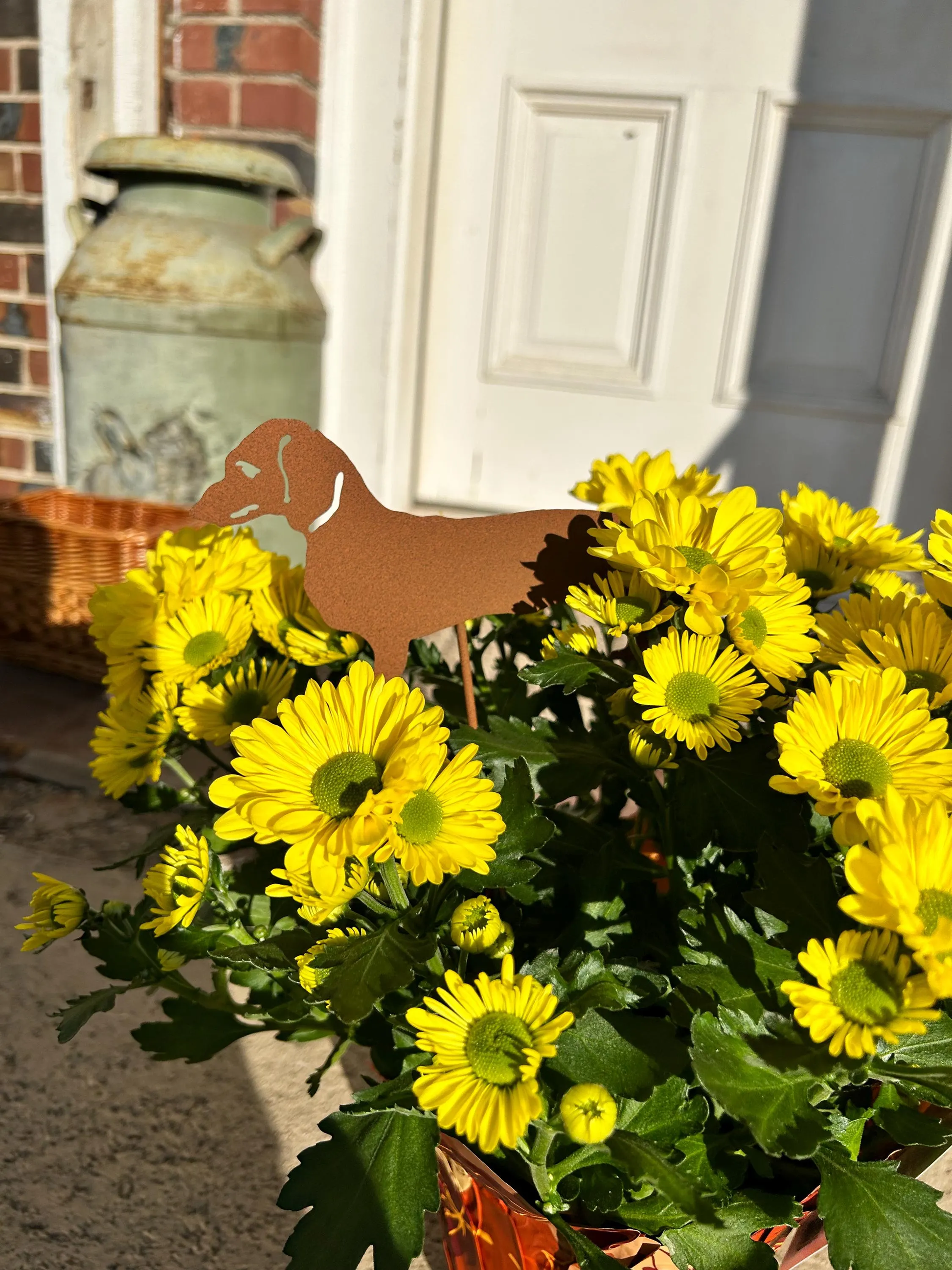 Dachshund Memorial Plant Stake rusted metal silhouette among bright yellow chrysanthemums on Tampa Home & Garden Store