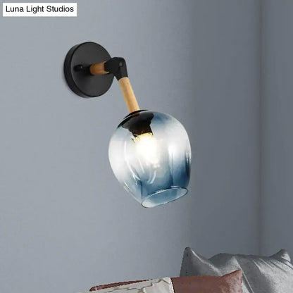 Blue glass wall sconce with wooden arm and black round mount on gray wall on Tampa Home & Garden Store