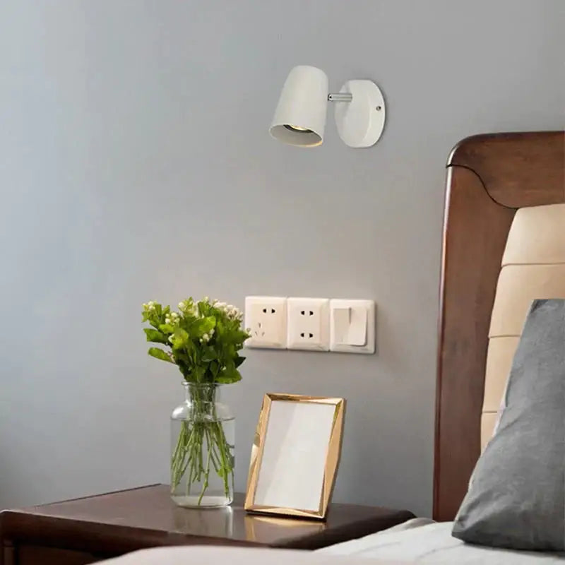 Nickel LED wall sconce Decorbites with white shade mounted on gray wall above bedside table on Tampa Home & Garden Store