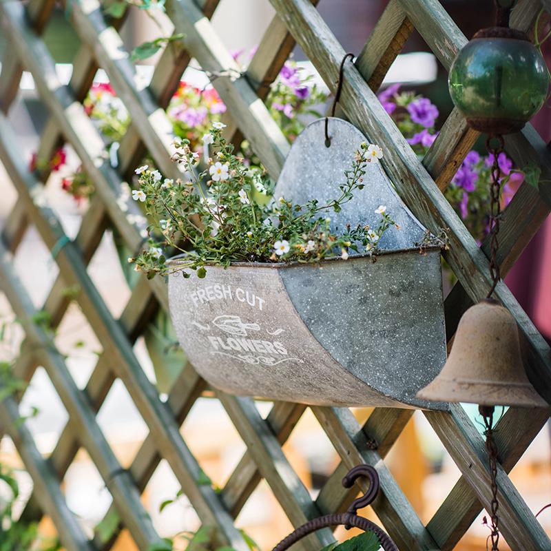 Iron Flower Wall Planter; galvanized gray metal with white flowers, hung on lattice on Tampa Home & Garden Store