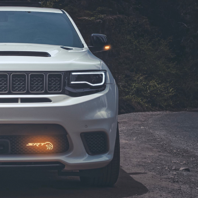 Jeep Trackhawk RGBW Flow Series LED Grill Emblem on front grille of white SUV with SRT badge on Tampa Home & Garden Store