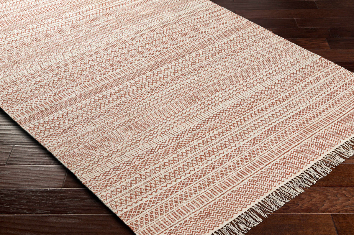 Kalinga red and cream flatweave wool rug with fringe on dark wood floor on Tampa Home & Garden Store