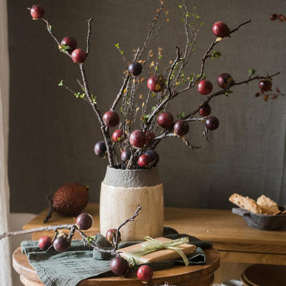 Khaki coarse pottery jar centerpiece with twig branches and red berries on a wooden table on Tampa Home & Garden Store