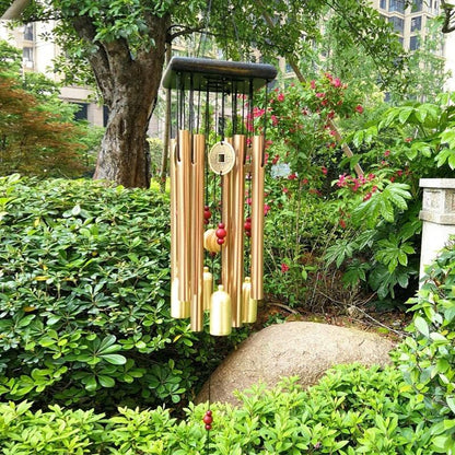 Large copper wind chime by Stevvex with vertical tubes and coin pendant in a garden on Tampa Home & Garden Store