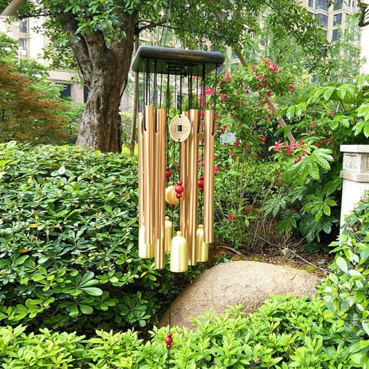 Large copper wind chime by Stevvex with vertical tubes and coin pendant in a garden on Tampa Home & Garden Store