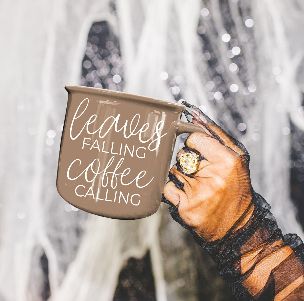 Leaves Falling mug by Gia Roma in tan ceramic with white script held by gloved hand on Tampa Home & Garden Store