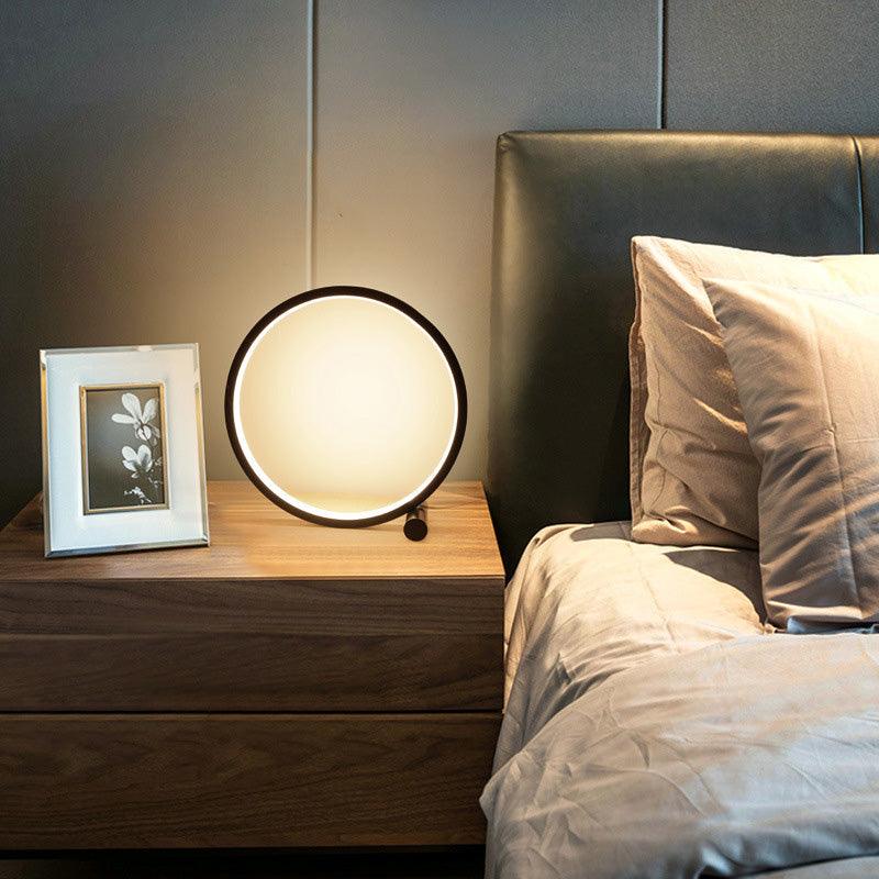 LED table lamp with black circular ring and warm glow on a wood nightstand beside a framed photo frame on Tampa Home & Garden Store