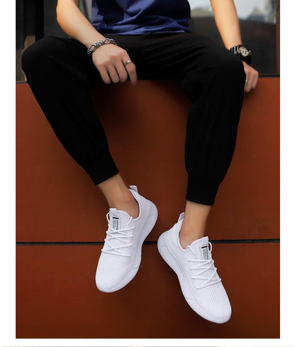 Stevvex men's white mesh running sneakers, breathable lightweight pair on model in black joggers on Tampa Home & Garden Store