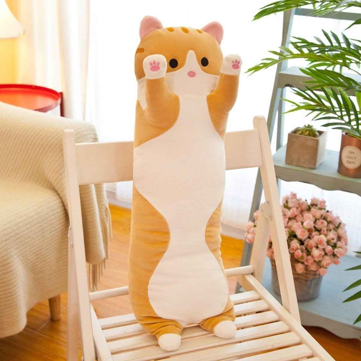 Long cat plush pillow 26-inch tan stuffed animal with pink paws, upright on a chair on Tampa Home & Garden Store