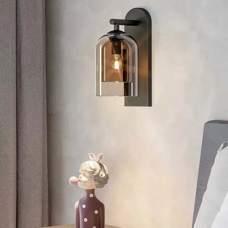 Amber glass wall sconce with black backplate and clear dome shade, Edison bulb lit on Tampa Home & Garden Store