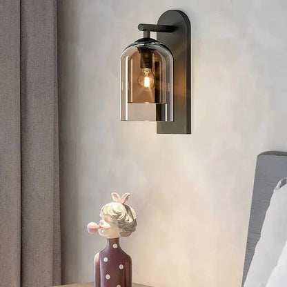 Amber glass wall sconce with black backplate and clear dome shade, Edison bulb lit on Tampa Home & Garden Store