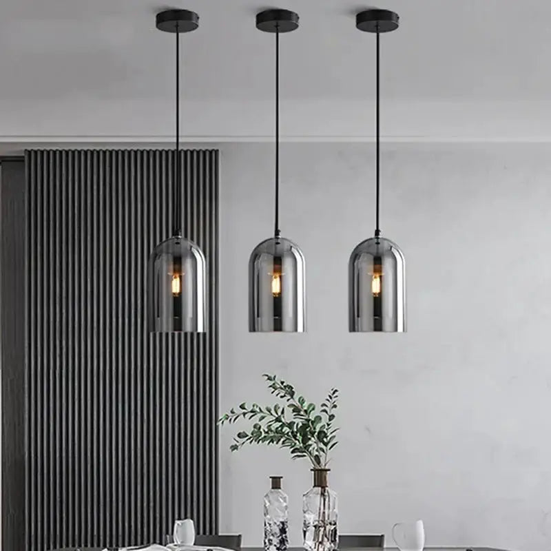 Three amber glass pendant lights with black cords and canopies over a modern dining space on Tampa Home & Garden Store
