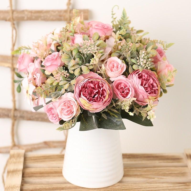 Silk rose bouquet with pink blooms and greenery in a white ceramic vase on a wooden table on Tampa Home & Garden Store