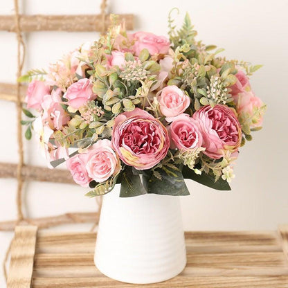 Silk rose bouquet with pink blooms and greenery in a white ceramic vase on a wooden table on Tampa Home & Garden Store