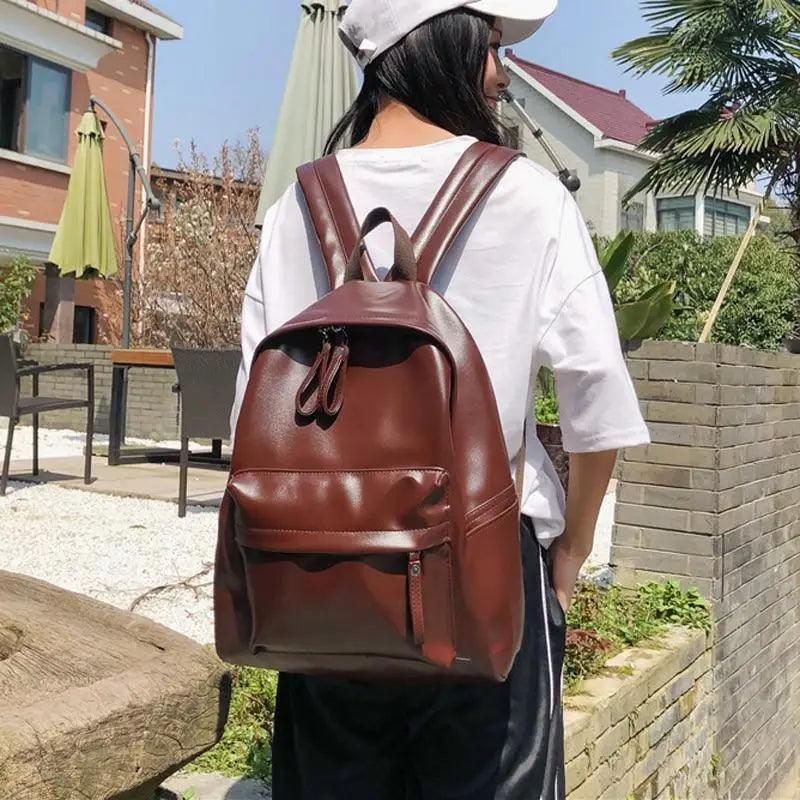 Stevvex brown PU leather backpack with front pocket and top zipper worn by a girl outdoors on Tampa Home & Garden Store