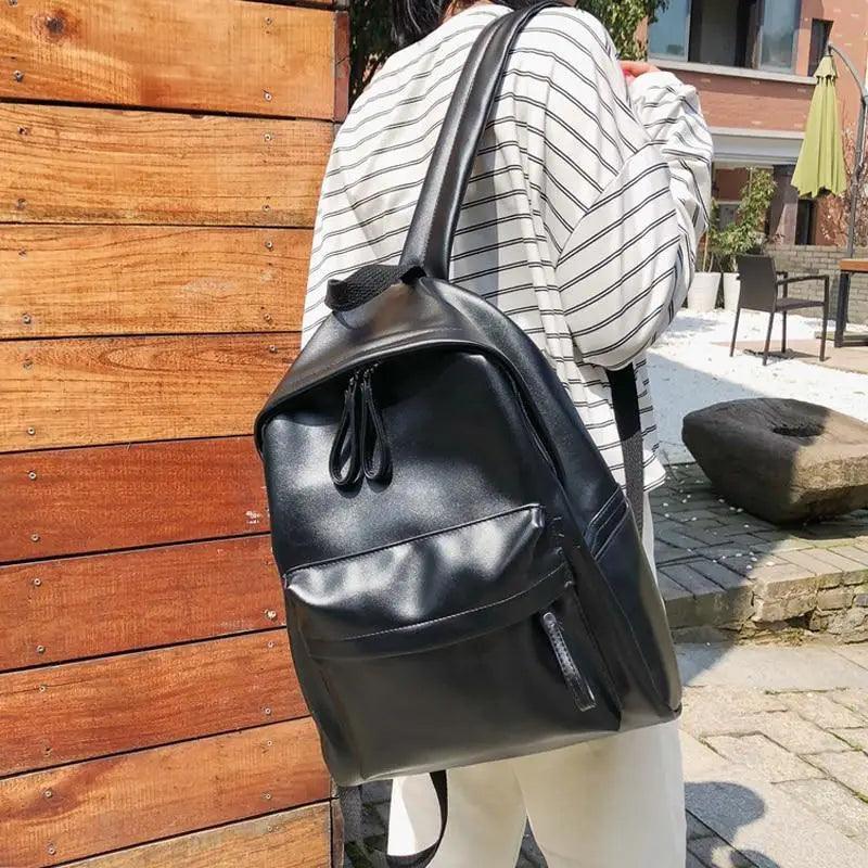 Stevvex black PU leather backpack with front zip pocket worn by a person in a striped shirt on Tampa Home & Garden Store