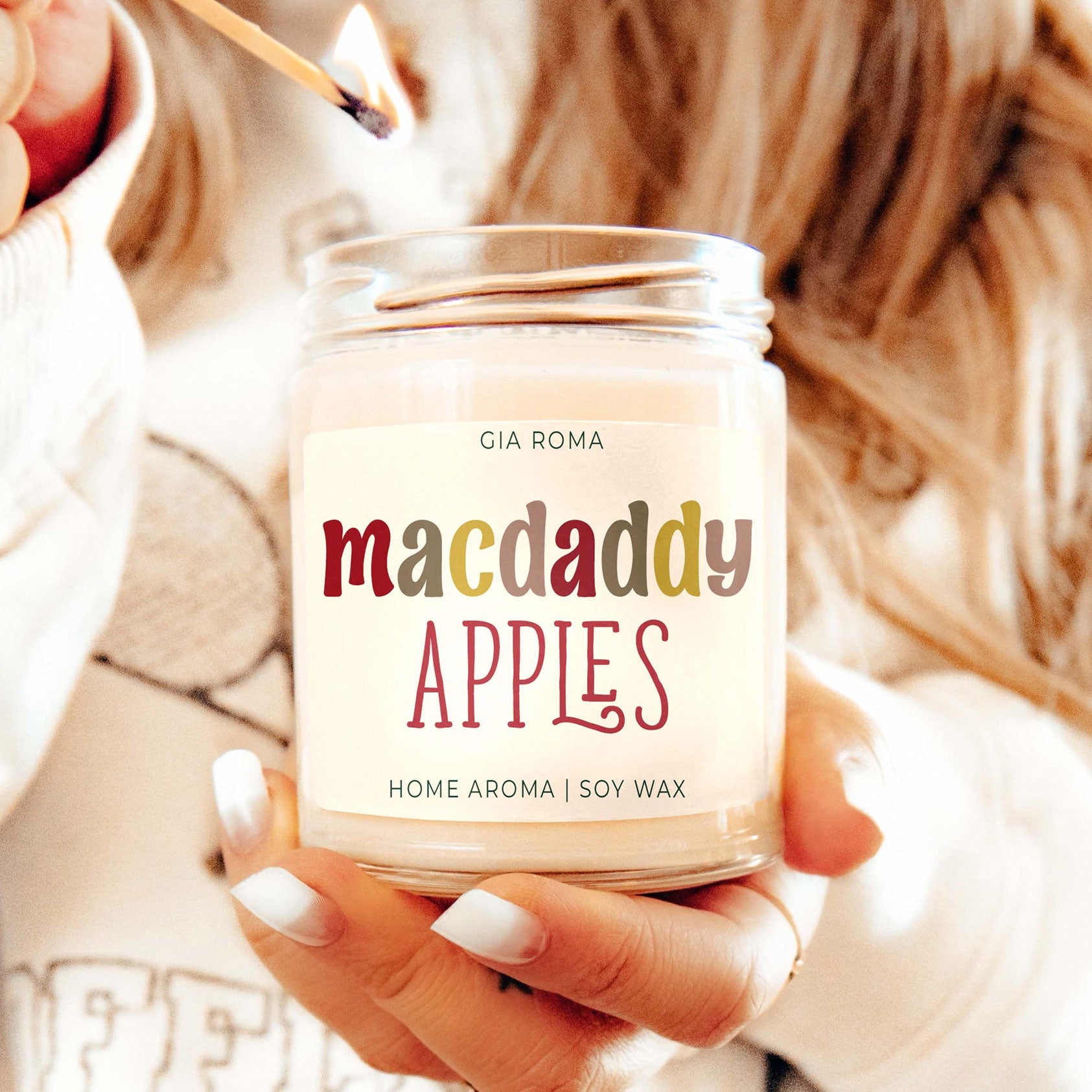 Mac Daddy Apples candle by Gia Roma in a clear glass jar with a lit match on Tampa Home & Garden Store