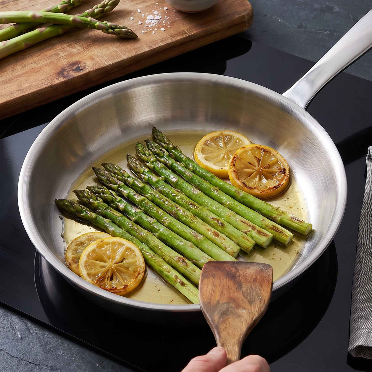 5-Ply stainless steel frying pan by Alva Cookware with asparagus spears and lemon slices cooking on Tampa Home & Garden Store