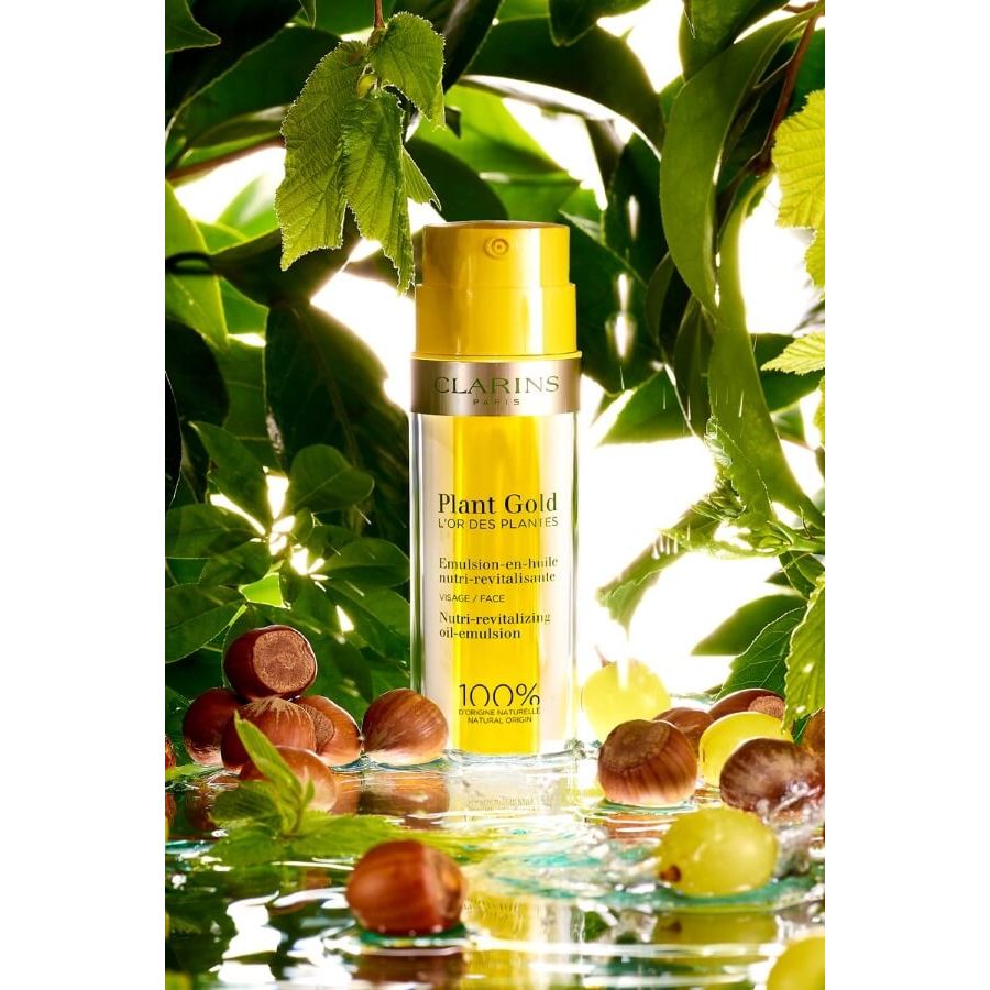 Clarins Plant Gold Nutri-Revitalizing Oil-Emulsion bottle with gold cap and oil near leaves on Tampa Home & Garden Store