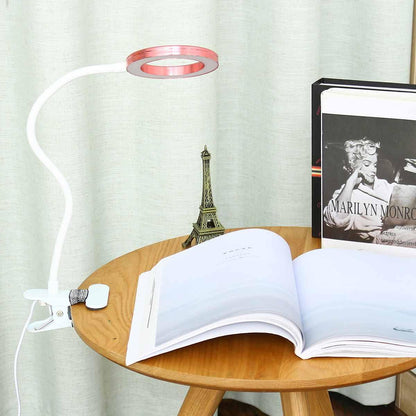 Stevvex white USB clip-on LED desk lamp with pink circular magnifier ring and flexible arm on round wood table beside open book on Tampa Home & Garden Store