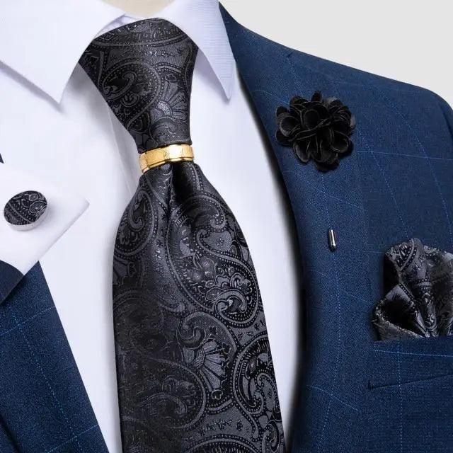 Men's black paisley silk necktie with gold tie clip against a blue suit on Tampa Home & Garden Store
